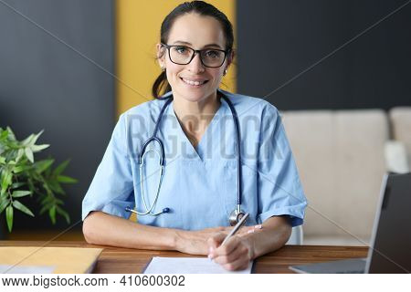 Woman Doctor With Glasses Filling Out Medical History. Medical Paperwork Concept
