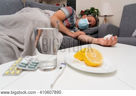 Sick Male Model Wearing Surgical Or Medical Protective Mask To Prevent Contamination Sleeping On Sof