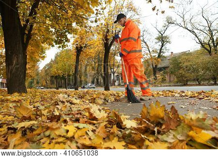 Street Cleaner Sweeping Fallen Leaves Outdoors On Autumn Day