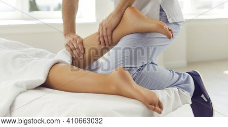 Physiotherapist, Reflexologist Or Professional Masseur Massaging Womans Calf In Wellness Center