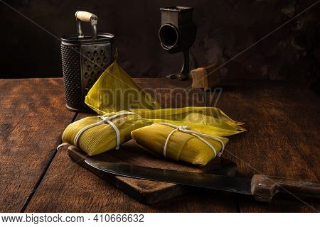 Pamonha, Brazilian Corn Food, Called Pamonha. On A Rustic Table With Knife And Old Corn Grater, Low