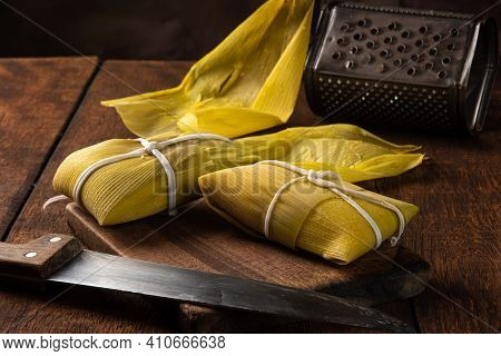 Pamonha, Brazilian Corn Food, Called Pamonha. On A Rustic Table With Knife And Old Corn Grater, Low