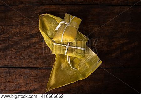 Pamonha, Brazilian Corn Food, Called Pamonha. On A Rustic Table With Knife, Low Key Portrait, Dark A