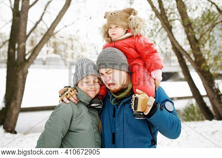 Portrait Of Funny Happy Family With One Sad Toddler In Winter Sporty Outfit Walking Outdoors In Snow