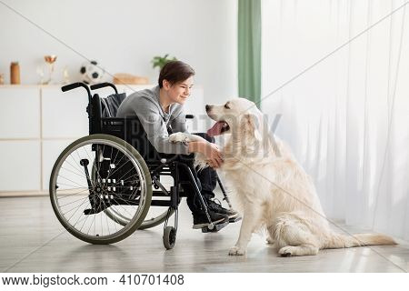 Happy Impaired Teenager Playing With His Dog At Home, Full Length Portrait. Cheerful Handicapped Ado