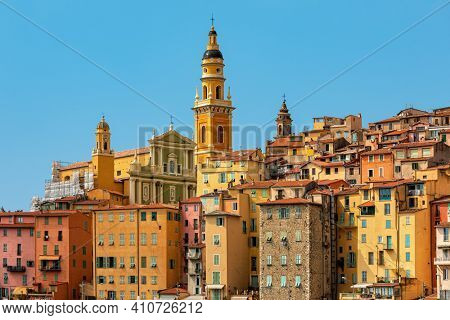 View of colorful houses and belfry of the Saint Michel Archange basilica under blue sky in Menton - small town on French Riviera.