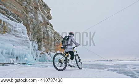 Woman Is Riding Bicycle Near The Ice Grotto. The Rock With Ice C