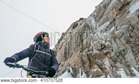 Man Is Riding Bicycle Near Ice Grotto. Rock With Ice Caves Icicl