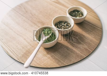 Green tea tasting, loose leaf dried leaves cups chinese teas rustic natural background. Spoon and teacups.