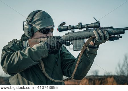 Portrait Of A Shooter With A Rifle. European Shoots A Rifle With A Optics Sight