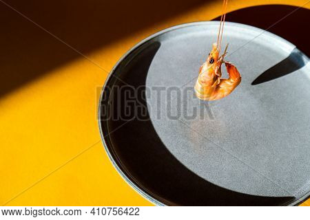 Balancing Flying Red Shrimp On A Gray Plate And Yellow Background. Trendy Colors. Minimalistic Conce