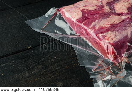 Cryovac Packed Meat Beef Brisket In Vacuum Set, On Black Wooden Table Background , With Copyspace  A