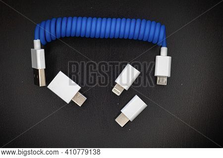 Blue Spiral Usb Cable With Adapters For Micro, Mini Usb And Lightning Isolated On Dark Background