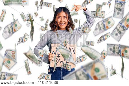 Young beautiful mixed race woman holding woman power banner pointing finger to one self smiling happy and proud