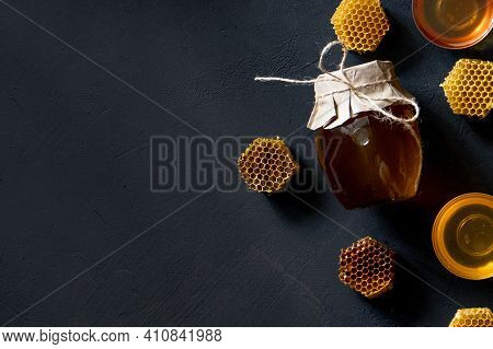 Jar Of Honey With Honeycomb On Black Table, Top View. Space For Text