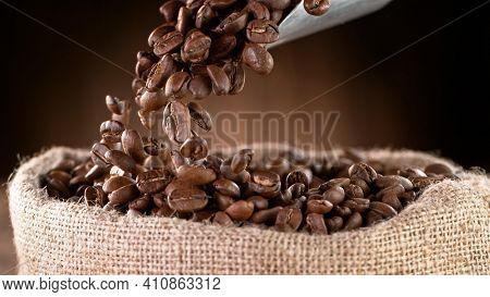 Falling Roasted Coffee Beans into Jute Bag, close-up.