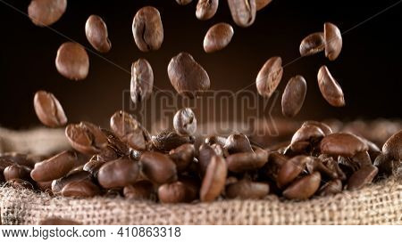 Falling Roasted Coffee Beans into Jute Bag, close-up.