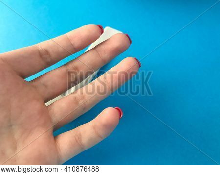On A Blue Matte Background Hand. Girls Fingers With Bright Red Manicure On The Medical Table. Plan T
