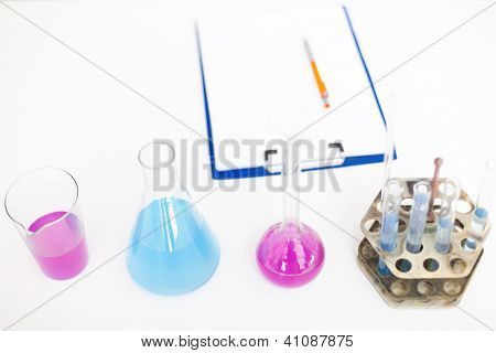 Chemical Flasks With Reagents And Clipboard Isolated Over White Background