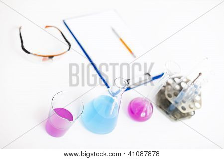 Chemical Flasks With Reagents And Clipboard Isolated Over White Background