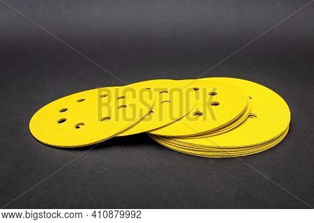 Sandpaper For Sanding Wood, On A Black Background. A Stack Of Yellow Round Sandpaper. Copy Space