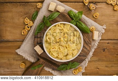 Tortellini Mignon On A Wooden Board With Basil And Parmesan. Specialties Of The Cuisine From Bologna