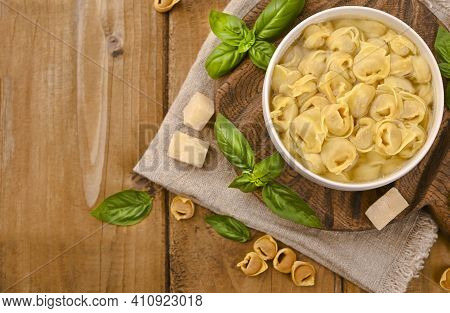 Tortellini Mignon On A Wooden Board With Basil And Parmesan. Specialties Of The Cuisine From Bologna
