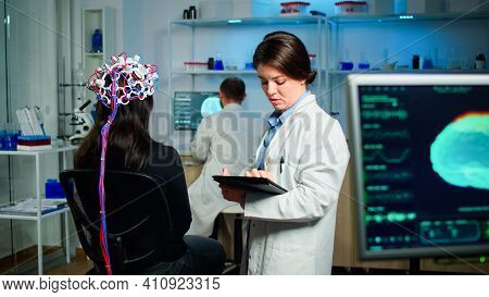 Back View Of Woman Patient Wearing Performant Brainwave Scanning Headset Sitting In Medical Neurolog