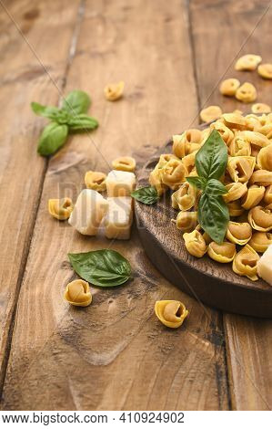 Tortellini Mignon On A Wooden Board With Basil And Parmesan. Specialties Of The Cuisine From Bologna
