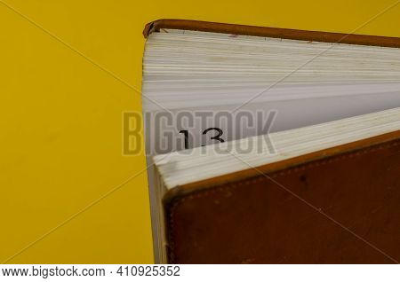Close-up Of An Old Diary Standing On The Endpaper Against A Yellow Background. Half-opened Diary Wit