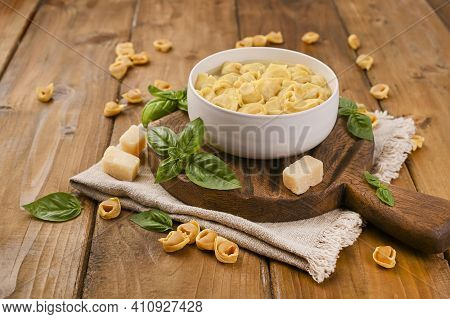 Tortellini Mignon On A Wooden Board With Basil And Parmesan. Specialties Of The Cuisine From Bologna
