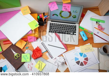 Messy Table With Laptop And Sticky Notes, Above View. Concept Of Being Overwhelmed By Work