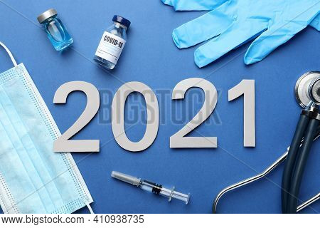 Flat Lay Composition With Coronavirus Vaccine And Number 2021 On Blue Background