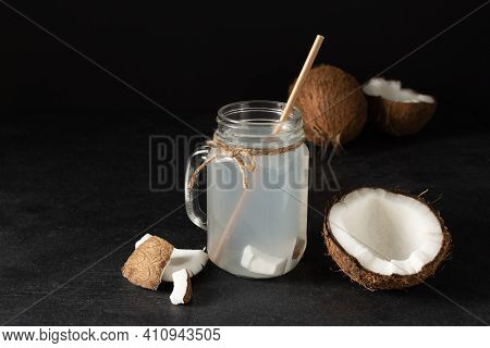 Coconut Water In A Glass Masson Jar On Black Table. Fresh Detox Coconut Juice.