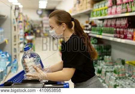 Woman Wearing Face Mask And Gloves Buying In Supermarket,smiling, Holding Water Botle. Panic Shoppin