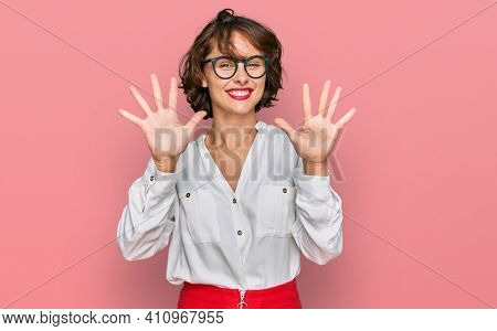 Young hispanic woman wearing business style and glasses showing and pointing up with fingers number ten while smiling confident and happy. 