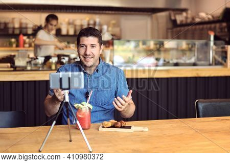 Social Media Influencer Or Food Blogger Creating Content Inside Small Restaurant - Man Sharing Live 