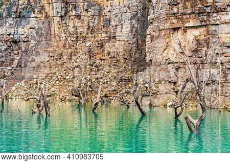 Sunken Trees With Dry Branches Getting Out Of The Water Of The Lake, Surrounded By Rock Walls Of Sed