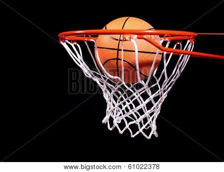 Basketball in hoop on black background