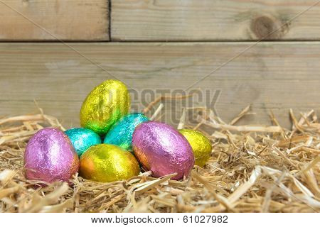 Foil covered chocolate Easter eggs in a straw nest in a barn
