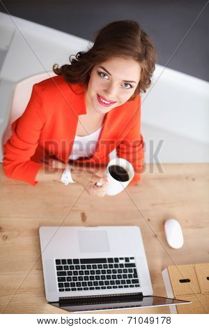 Attractive woman sitting at desk in office, working with laptop