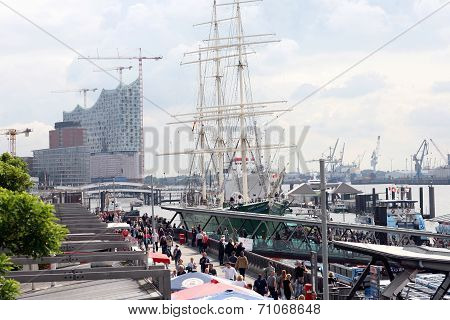HAMBURG, GERMANY - AUGUST 31, 2014: Elbphilharmonie, philharmonic orchestra hall under construction, harbour city. Municipal financial planning disaster. In front sailing ship Rickmer Rickmers.
