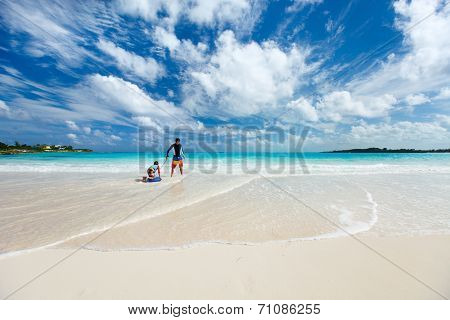 Beautiful tropical beach at Exuma Bahamas with father and son having fun