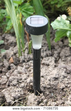 A small lamp with solar battery on a ground  in a dacha garden