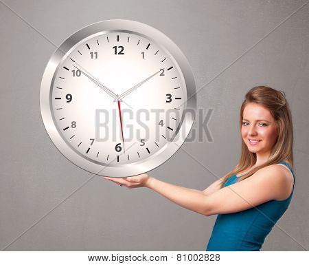 Attractive young lady holding a huge clock