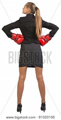 Businesswoman wearing boxing gloves standing akimbo