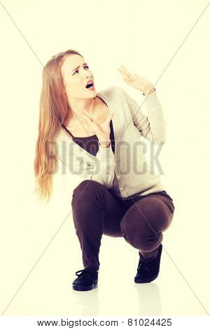 Beautiful cascaual woman is crouching from sth heavy above her.