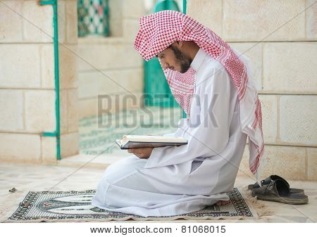 Young Arabic Muslim man reading Koran and praying