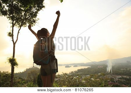 heering woman hiker open arms at mountain peak