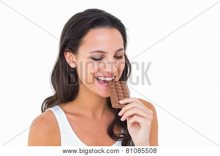 Pretty brunette eating bar of chocolate on white background